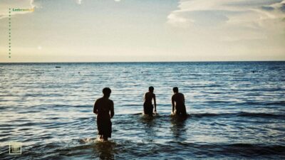 Tre mænd, der bader i havet.