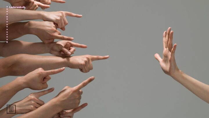 En hånd holdes op som stopsignal mod et hav af hænder, der peger fingre.