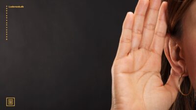 en persons øre med en hånd oppe, der viser at man lytter