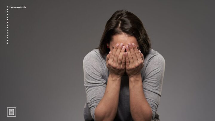 kvinde der holder hænderne for hovedet mens hun sidder ned