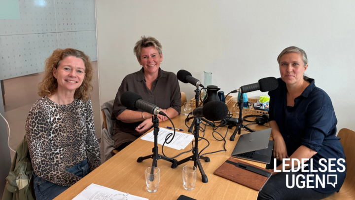 Tre kvinder sidder rundt om et bord med podcastudstyr.